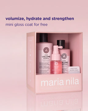 Maria Nila hair care set in a pink box with three bottles: Pure Volume Shampoo, Pure Volume Conditioner, and a pink mini gloss coat spray, with promotional text above on a pink gradient background.