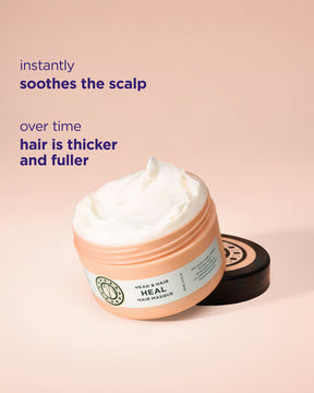 A jar of Head & Hair Heal hair mask with white cream visible on top, shown on a soft peach background with descriptive text about scalp health and hair thickness. The product jar is peach-colored with a white label and a black lid resting beside it.