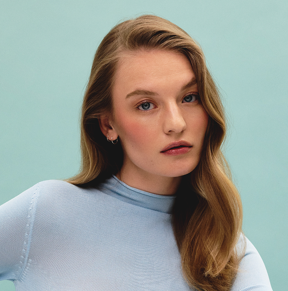 Model with dark blonde hair against a blue background